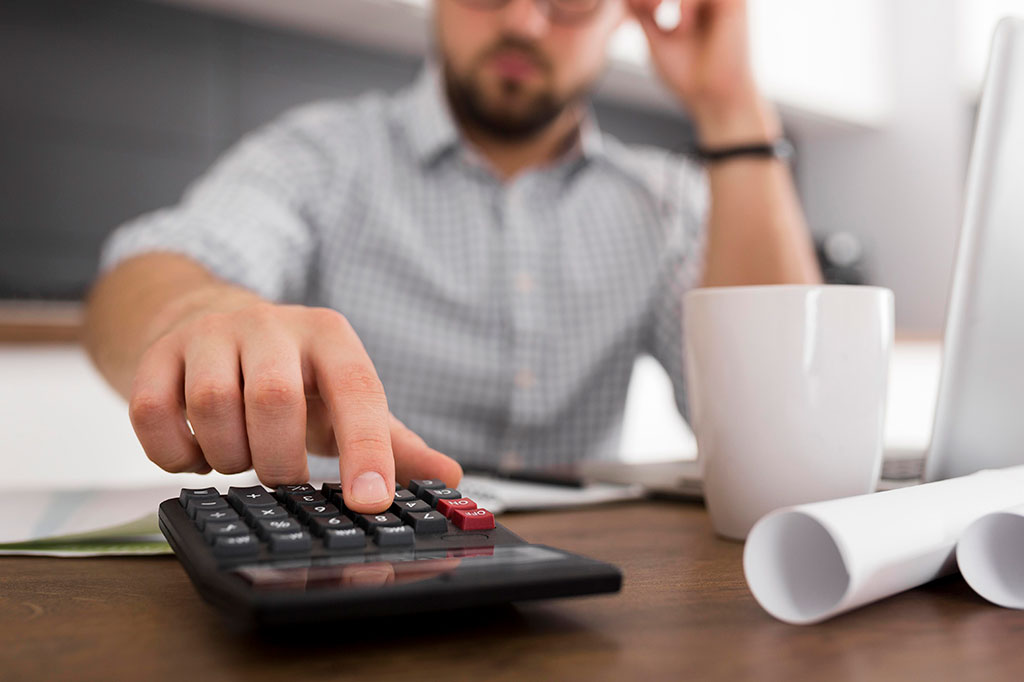 Мужчна считает сумму налогового вычета на калькуляторе